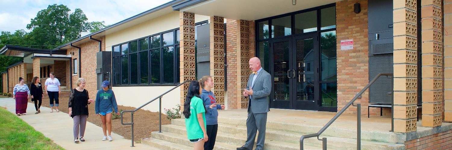 Photo of a campus administrator talking with a student outside of a campus building