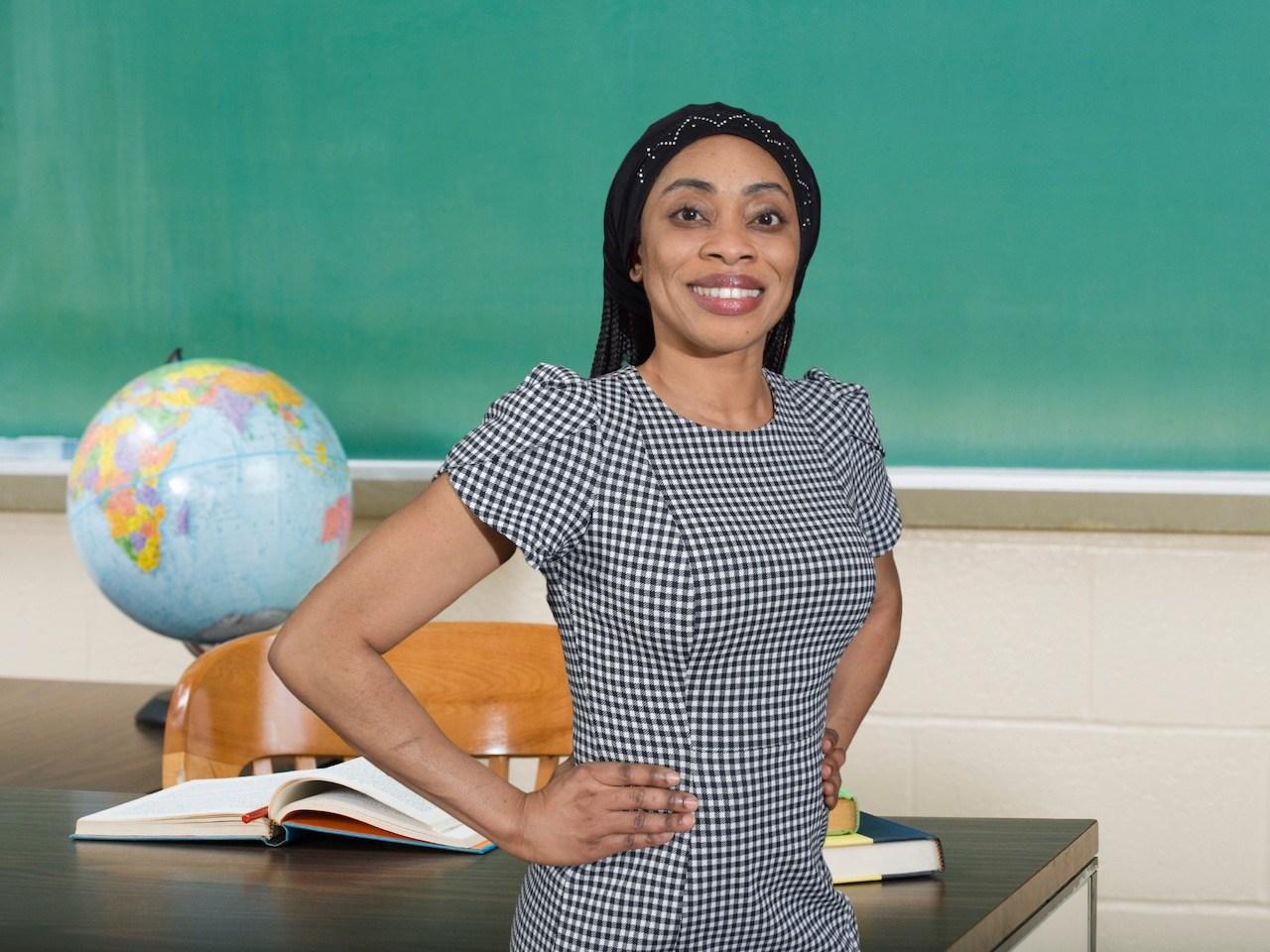 Dr. Anne Keke standing in front of a desk with a globe and smiling